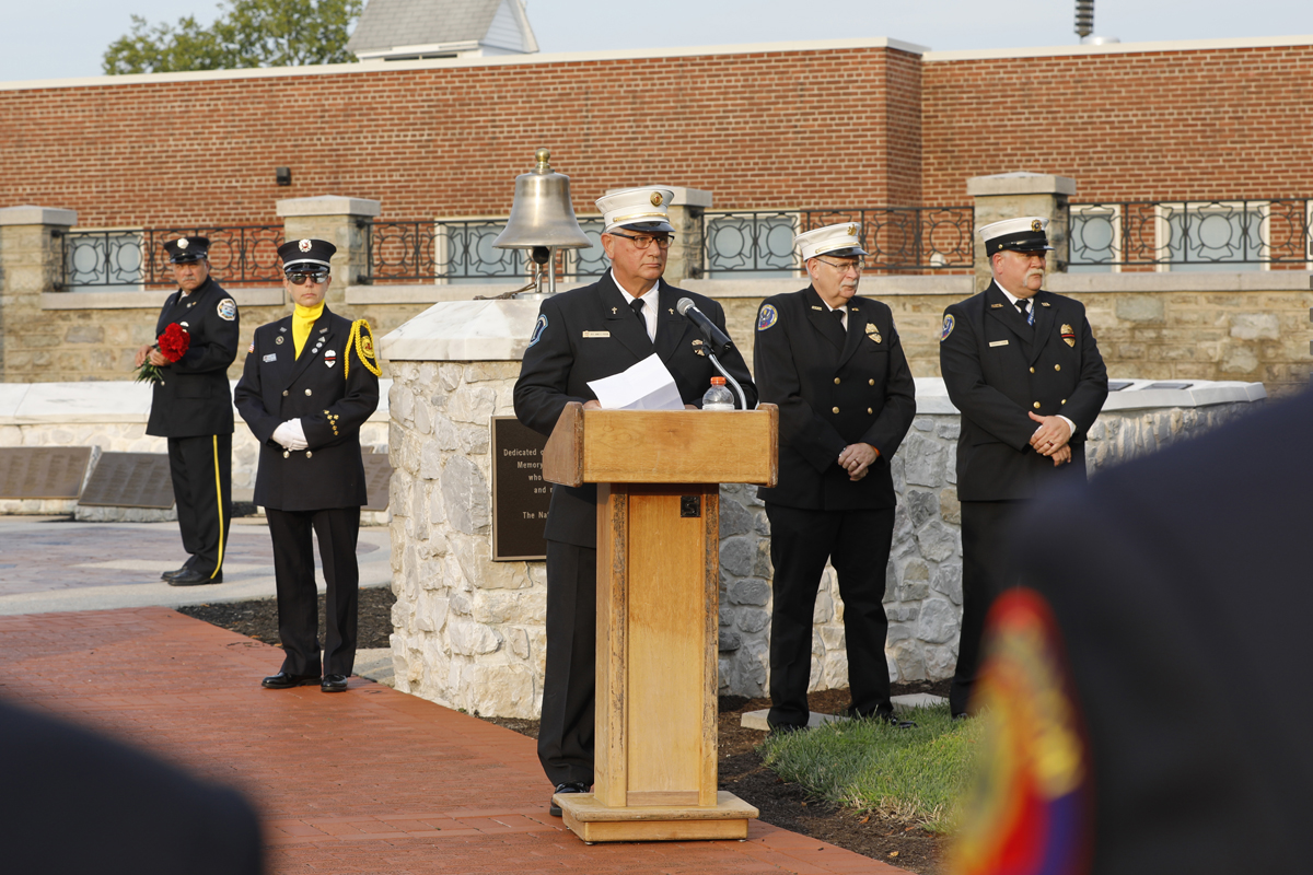 Firefighters in uniform with one standing at a podium